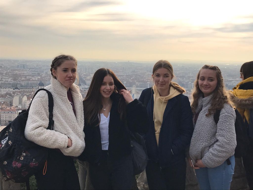 Four students standing in front of a panoramic view of the city