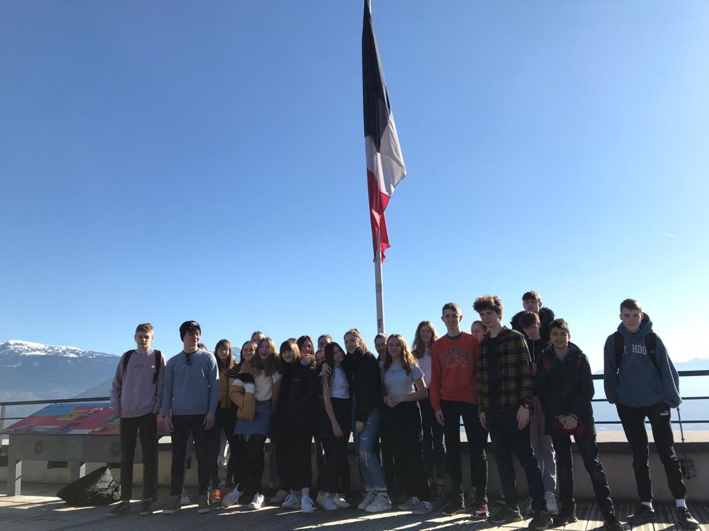 Students standing before the French flag