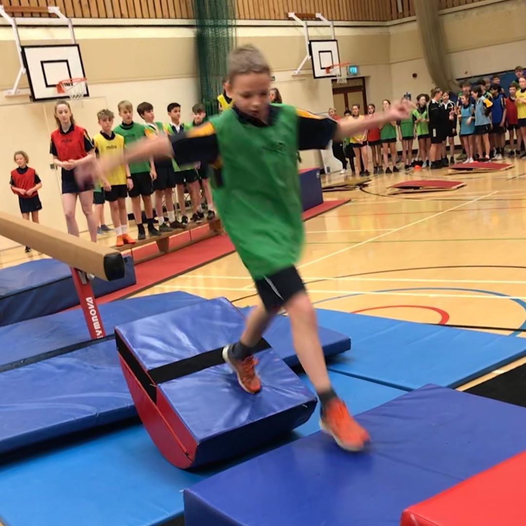 Boy on obstacle course - a queue of other competitors waiting their turn behind.
