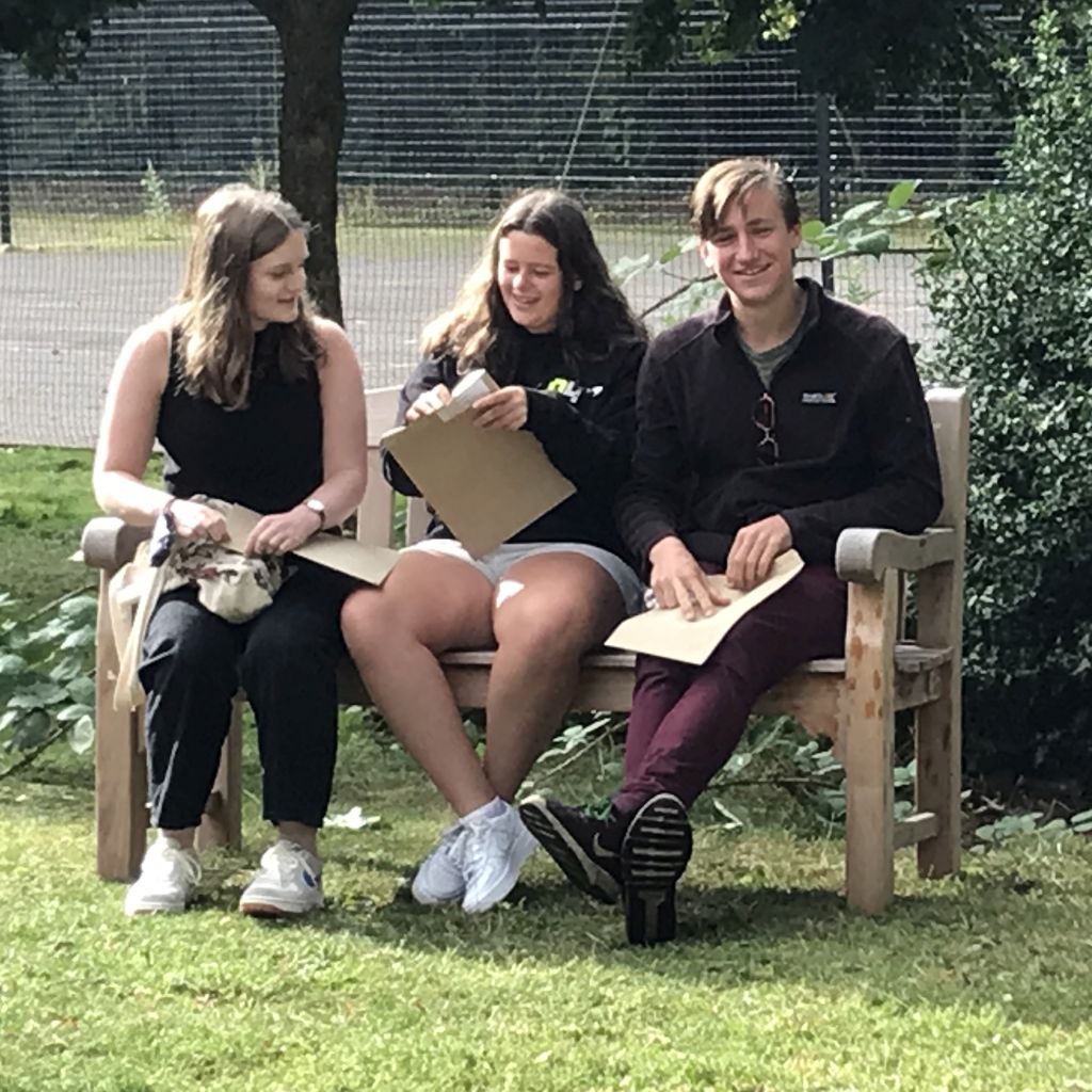 Students checking their results, sitting on a bench